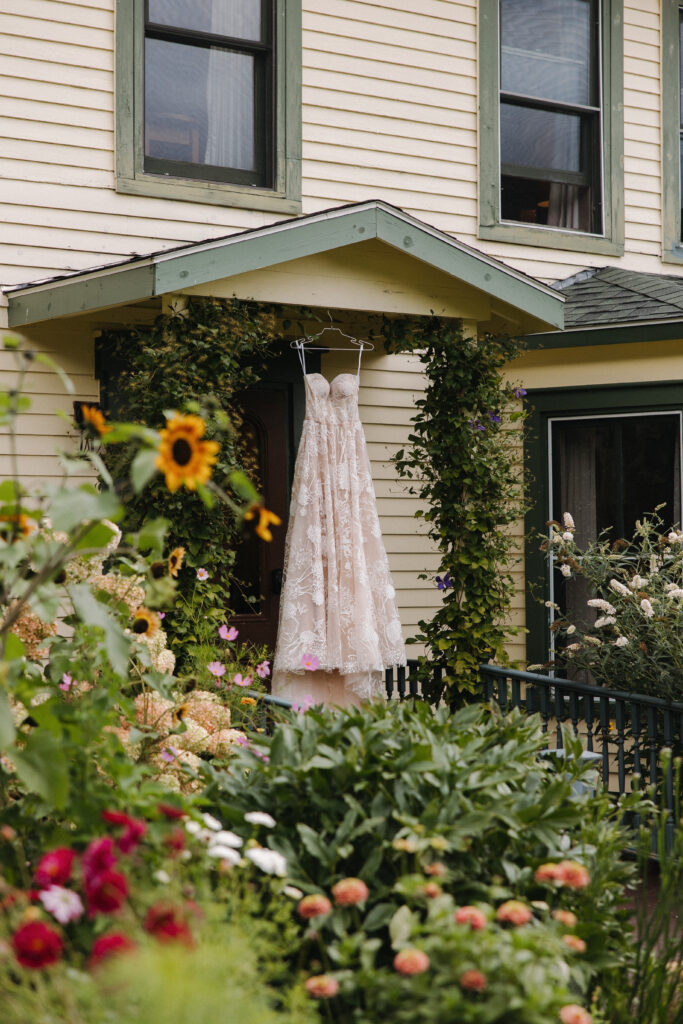dress shot hanging on a door frame outside a house with wildflowers