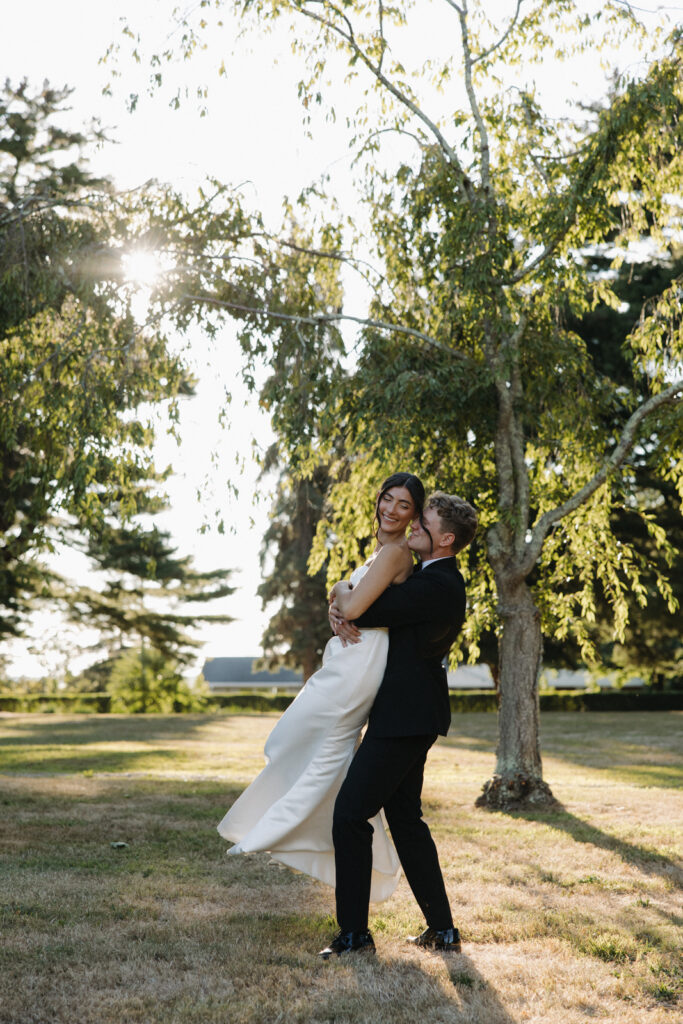 Connecticut outdoor, summer wedding. The groom is holding the bride and twirling her.