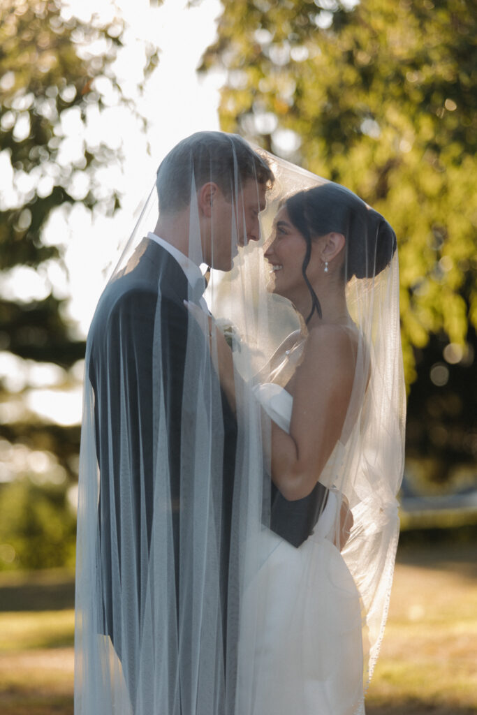 The bride and groom are under the veil, taking a moment before their outdoor ceremony. 