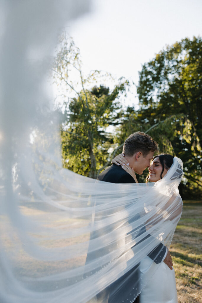 Motion photo of the white lace veil swirling to the side of the bride and groom. 