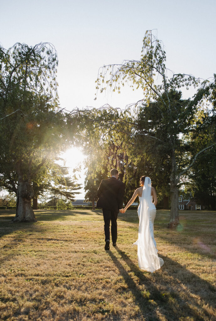 The bride and groom running off into the sun at their Connecticut outdoor summer wedding. 