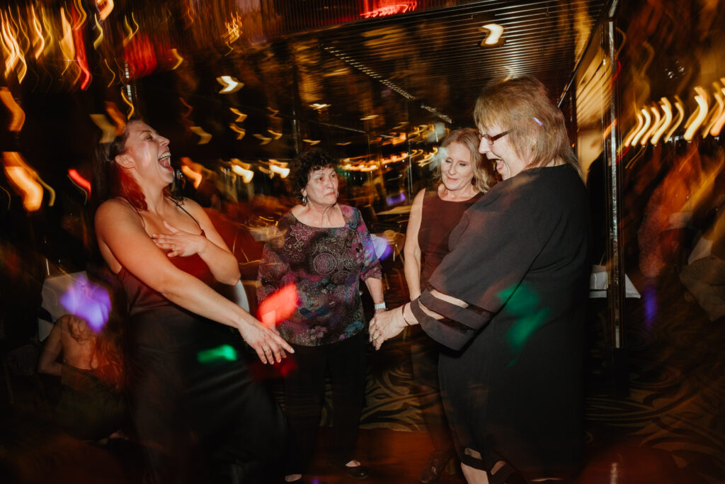 Four women are dancing at a wedding rehearsal dinner: motion and documentary wedding photography. 
