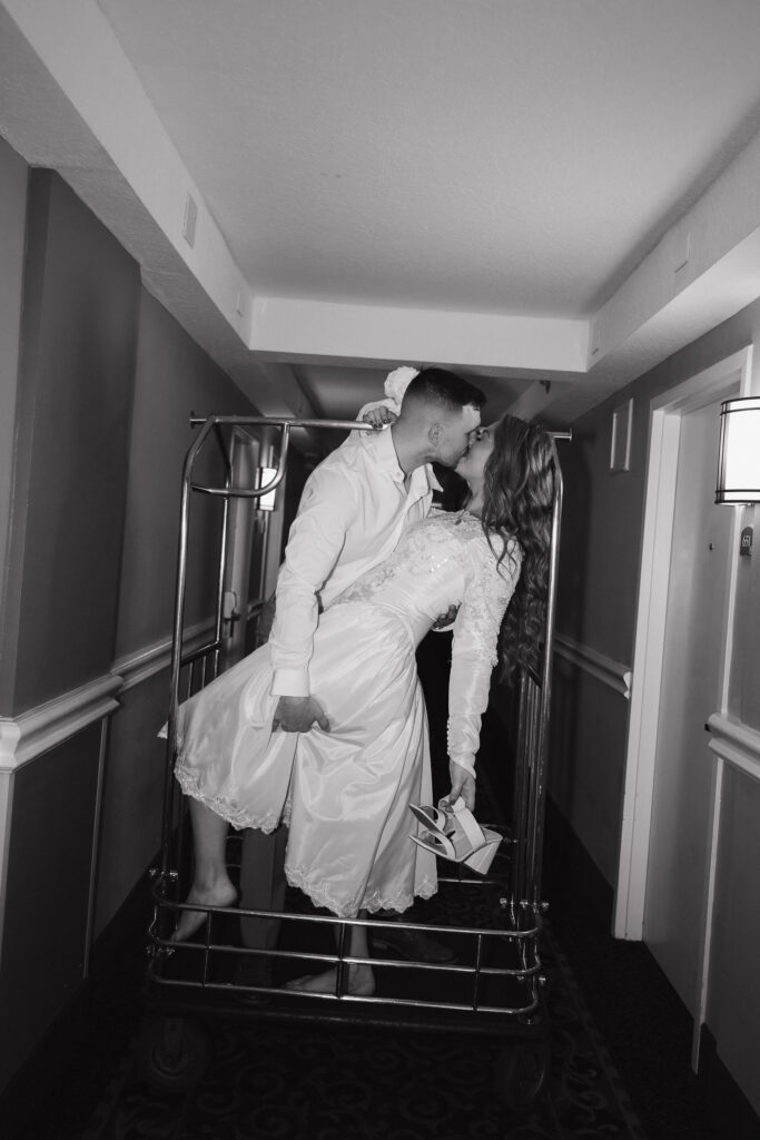 Black and white editorial wedding photo of the bride and groom in a hotel hallway after their wedding rehearsal.