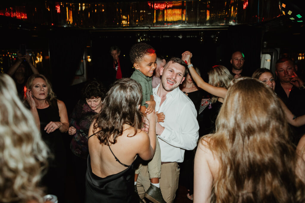 Family dancing at a dinner cruise wedding rehearsal, celebrating the soon-to-be bride and groom. 