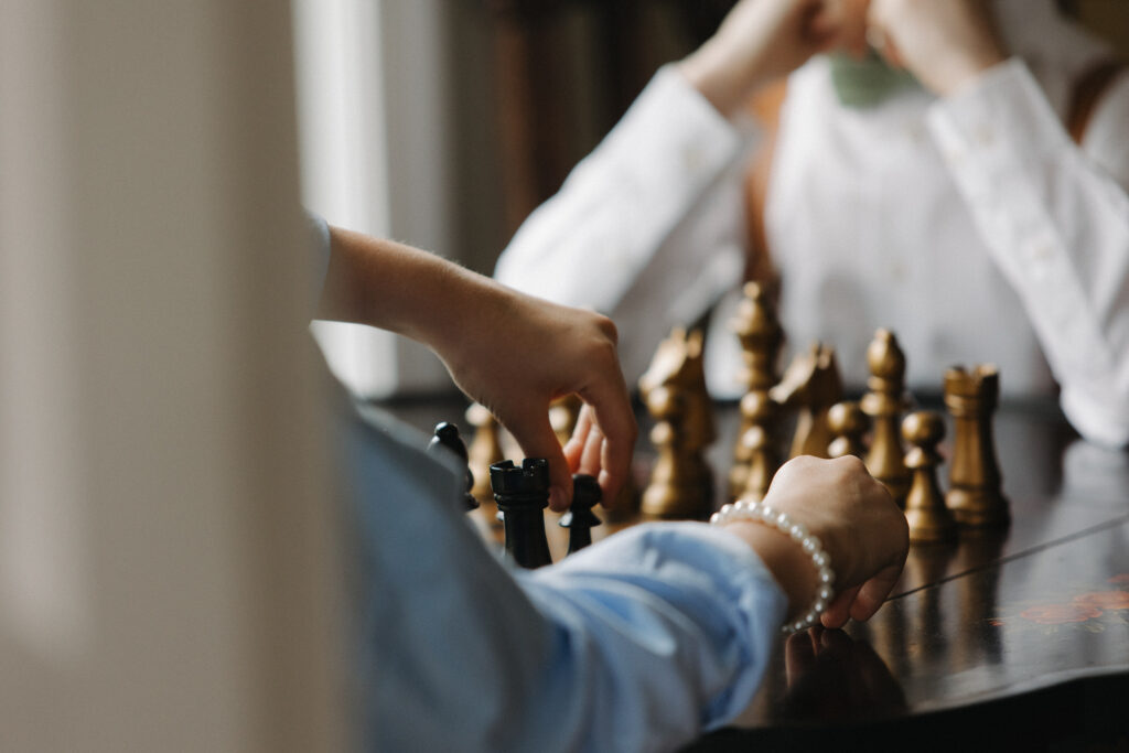 Two groomsmen playing chess before the wedding ceremony at a Connecticut luxury wedding.