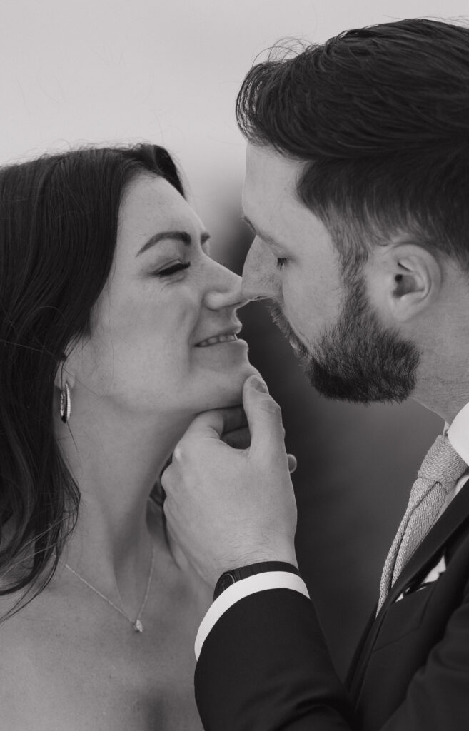 Black-and-white documentary style wedding photography capturing the bride and groom up close smiling. 
