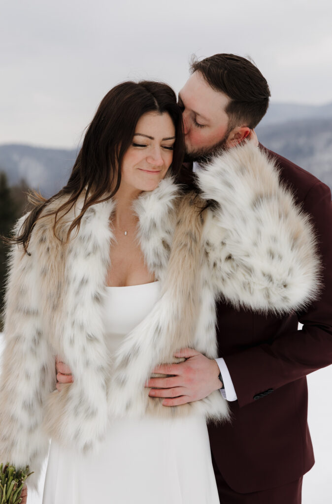 Documentary-style wedding photography captures the bride and groom sharing a moment together after their outdoor winter wedding ceremony.