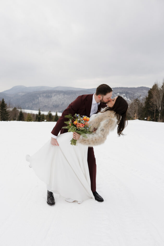 The bride and groom share a kiss after their dreamy winter wedding outside in the Adirondack Mountains. 