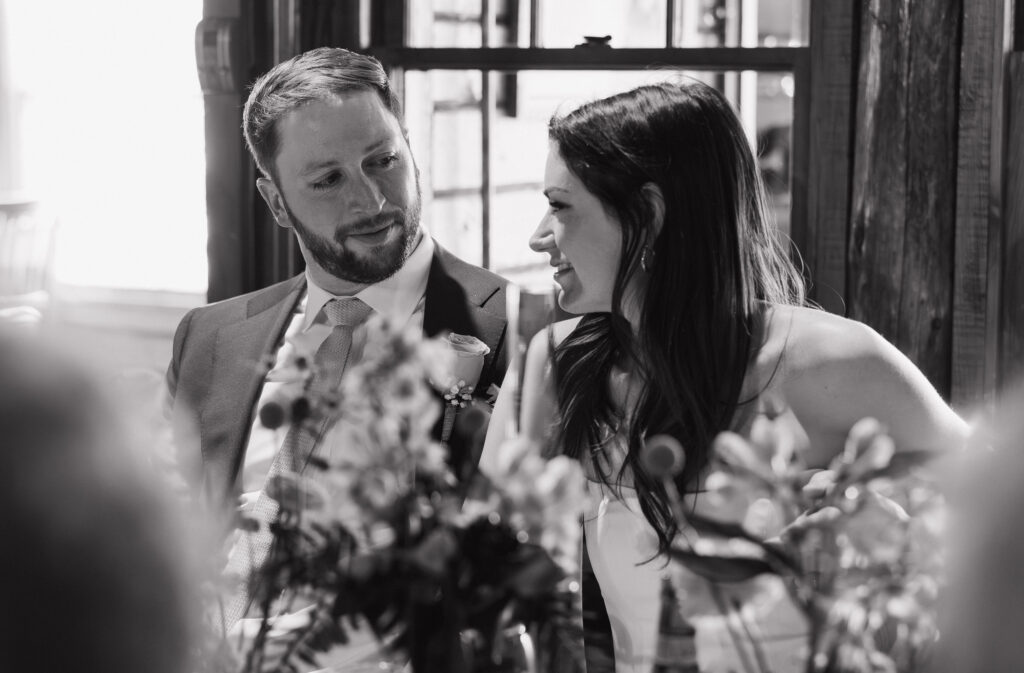 The bride and groom are enjoying their time together at their cozy lodge reception at Garnet Hill Lodge in the Adirondack Mountains. Black-and-white documentary style wedding photography. 