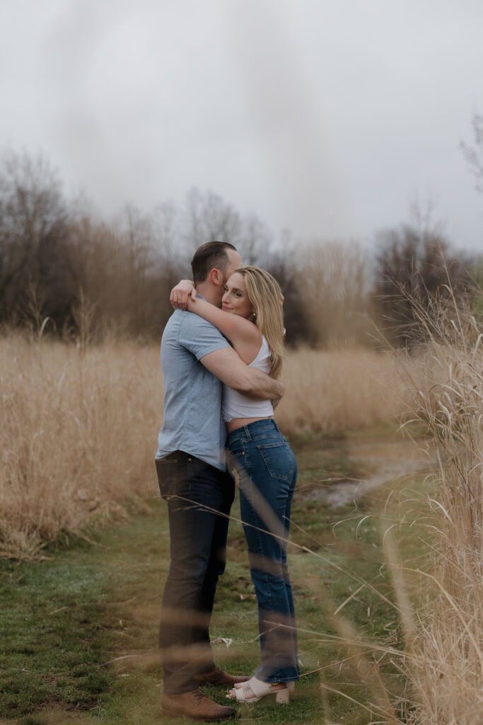 Candid photo of a couple embracing in tall grass during a Connecticut engagement session.