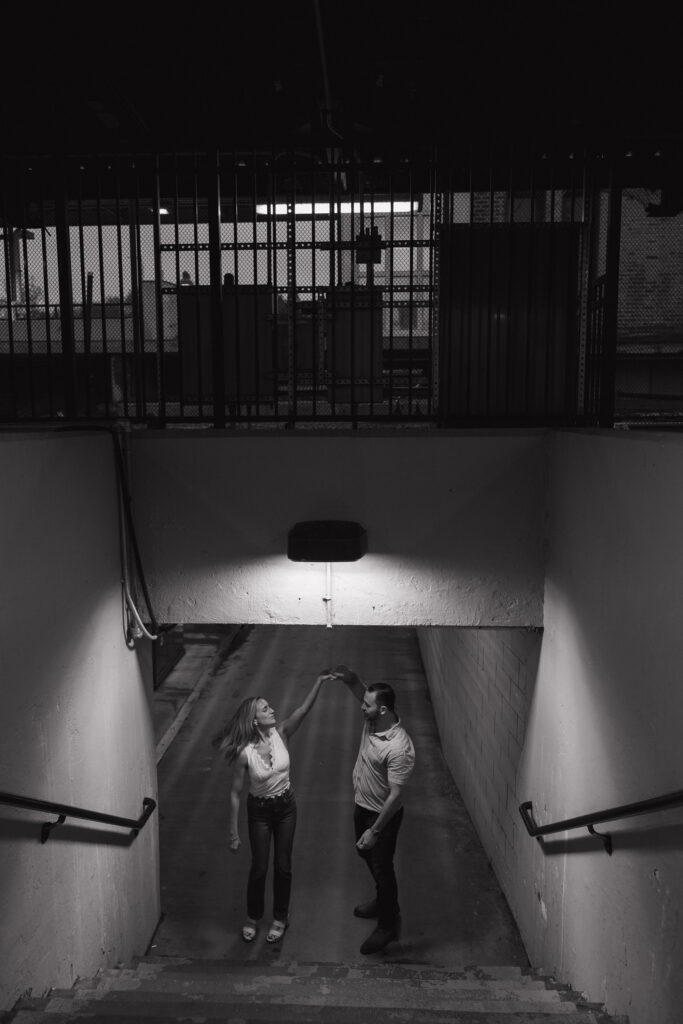 black and white photo of couple dancing under a light at the train station 