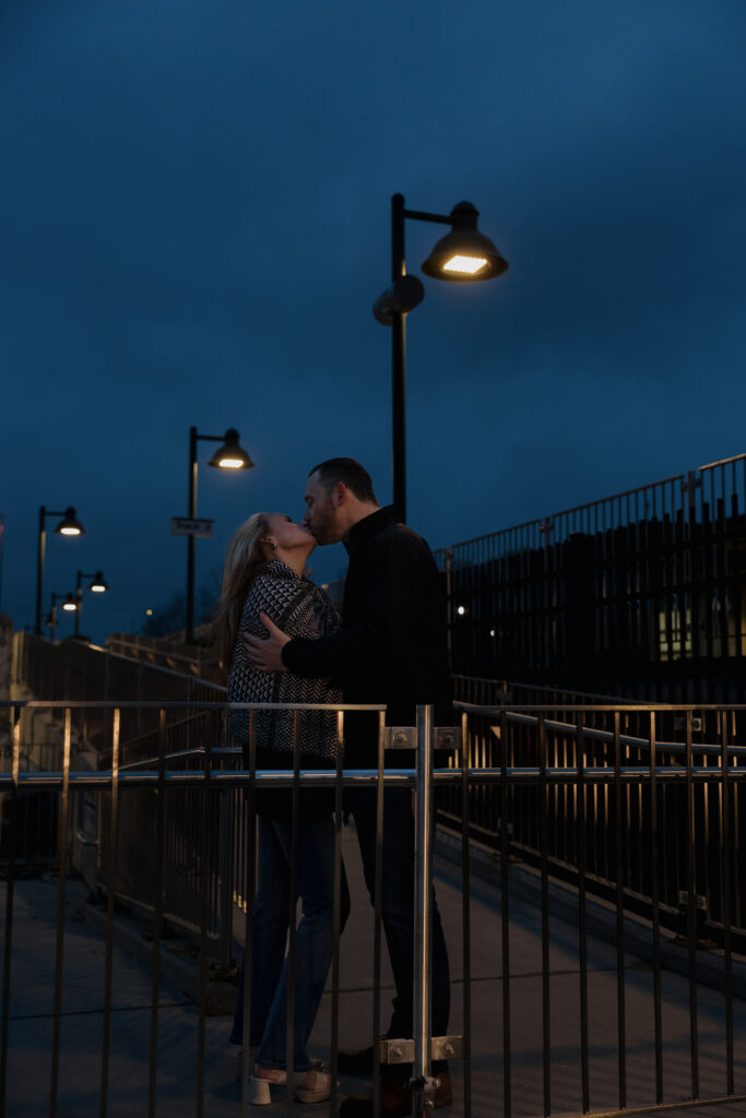 Couple embracing on a train platform at night during a romantic Connecticut engagement session.