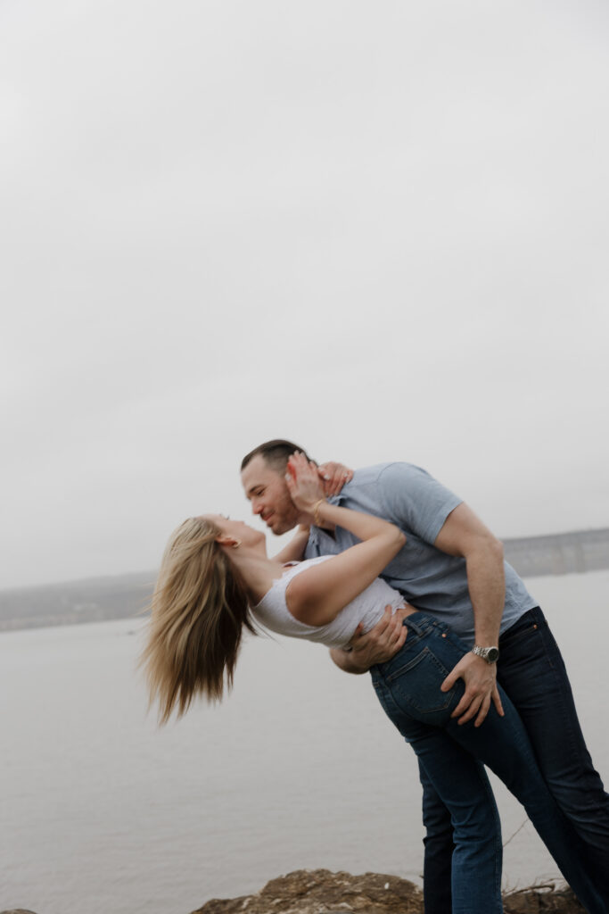 Romantic dip pose of a couple overlooking the water during a  shoreline couples photography session.