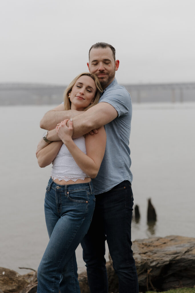 Close-up of a couple embracing during a couples photography session with a soft, overcast sky.
