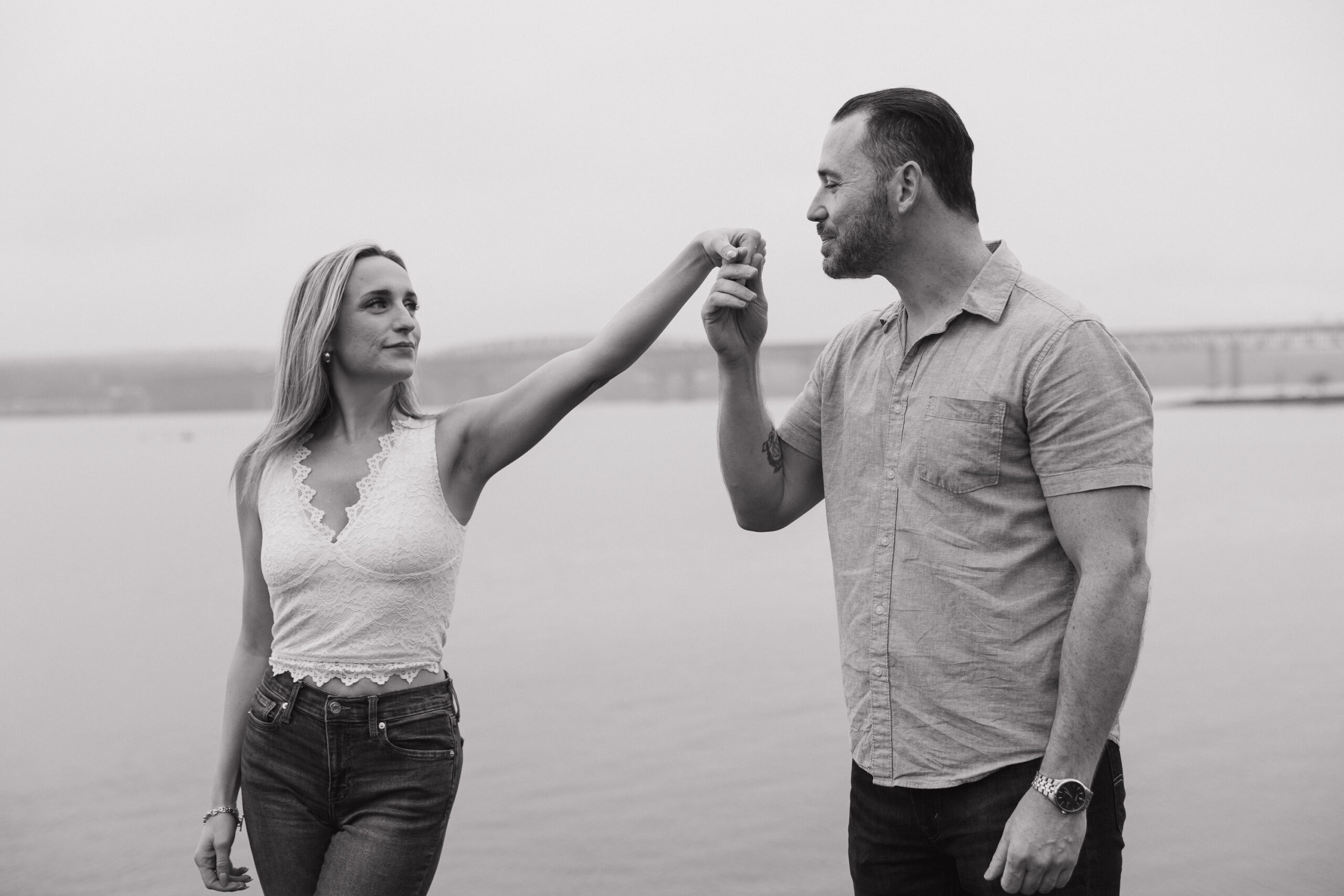 Couple holding hands on a rocky beach during a Guilford Connecticut engagement session by the water.