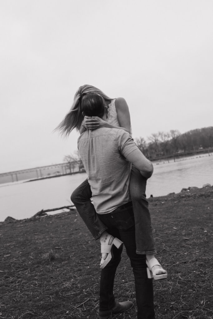 Black and white candid of a couple laughing together by the shoreline during a CT engagement session.