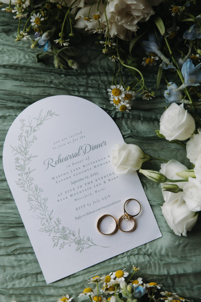 detail photo of a wedding invitation with florals and rings 
